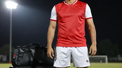 A 34-year-old right-back with a rugged build, wearing a red jersey with white sleeves and white shorts, with a black kit...