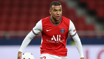 A tight action crop of an anonymous Paris FC player in a red jersey with white sleeves and white shorts, holding a white...