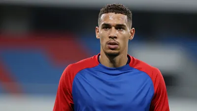 Mid-30s athletic forward, waist-up, intense gaze, sweat-glazed skin, wearing a plain blue and red training top (solid...