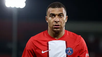 A close-up of a Paris FC player, wearing a red jersey with white shorts, looking concerned as he stands on the pitch...