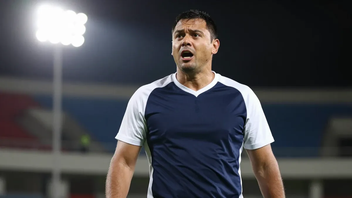 A 35-year-old male coach with a strong build, wearing a navy blue and white kit, photographed with an 85mm f/1.4 lens...