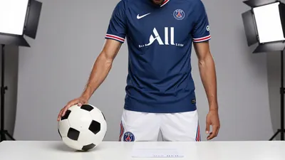 A photorealistic image of an anonymous Paris FC player in a blue jersey with white shorts and blue socks, holding a...