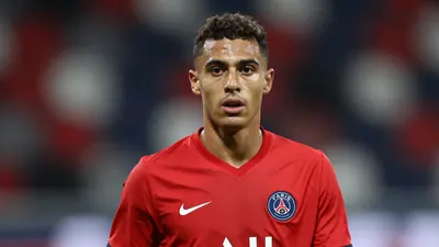 A mid-20s anonymous Paris FC midfielder, waist-up, wearing a solid red jersey, focused expression, shallow depth of field...