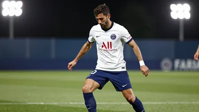 A 30-year-old Paris FC midfielder in a white jersey with blue shorts and blue socks, playing a one-on-one move against a...