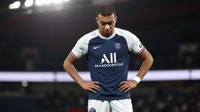 A tight waist-up shot of a young, anonymous Paris FC player with a determined expression, wearing a navy blue jersey with...