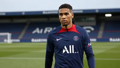 A determined 25-year-old Paris FC midfielder, wearing a plain blue and red training top, stands on the Stade Charléty...